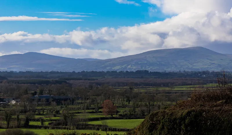 Rolling hills above patchwork green fields under a blue sky