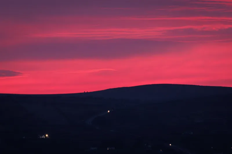 Crimson sunset sky over a silhouetted hill